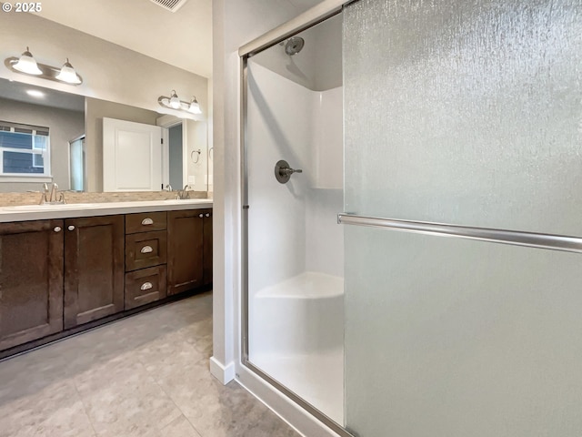 bathroom with double vanity, a shower stall, and a sink