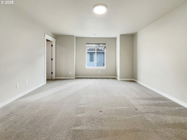 spare room featuring light carpet, visible vents, and baseboards