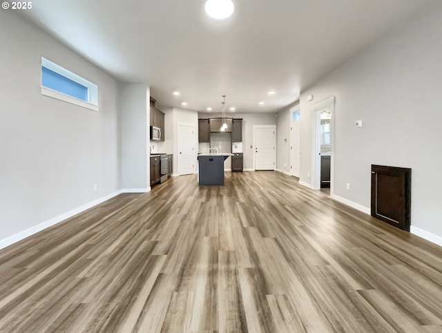 unfurnished living room featuring dark wood-type flooring, recessed lighting, a sink, and baseboards