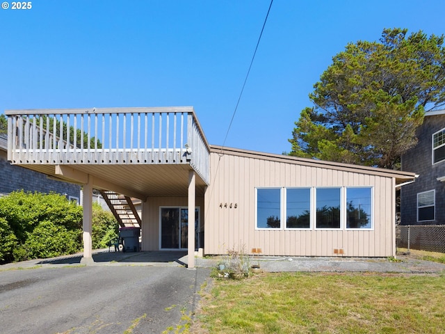 view of front facade featuring aphalt driveway, fence, stairway, crawl space, and a carport