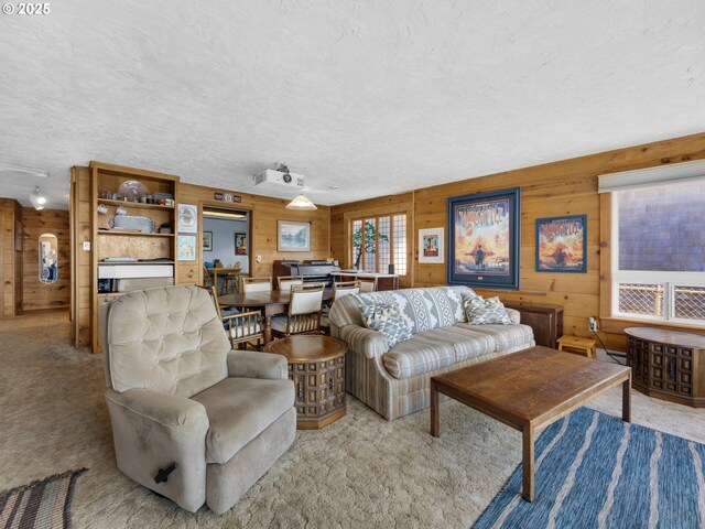 living area featuring light colored carpet, wooden walls, and a textured ceiling