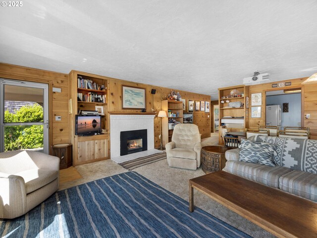 carpeted living room featuring wood walls and a fireplace