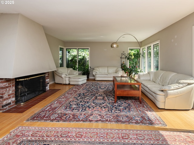living room with a brick fireplace and wood finished floors