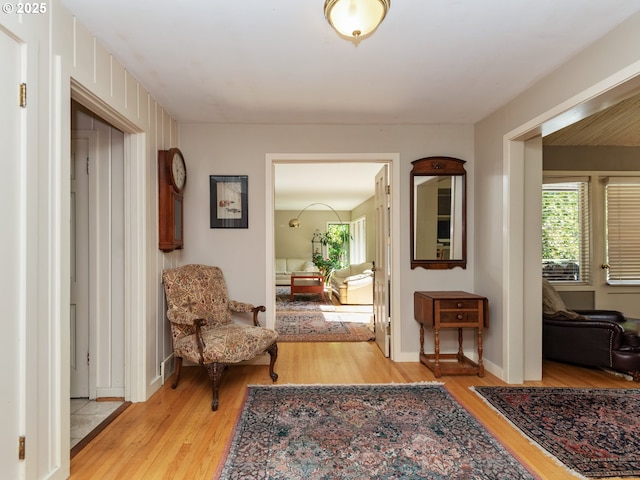hallway with baseboards, plenty of natural light, and light wood-type flooring