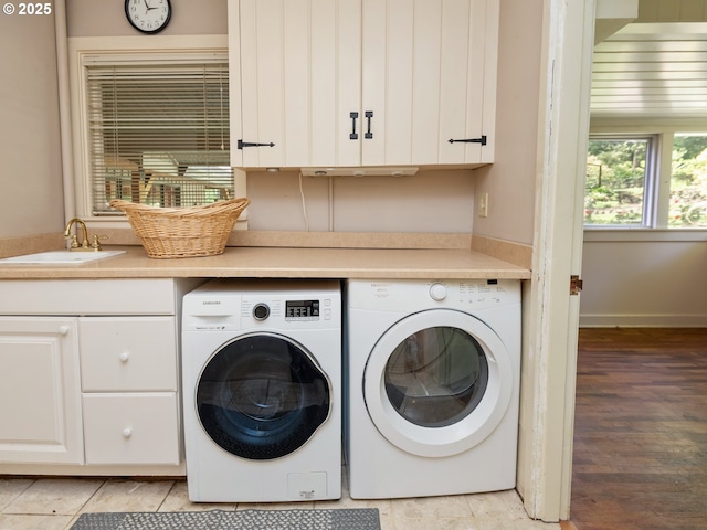 washroom with cabinet space, a sink, washer and clothes dryer, and light wood finished floors