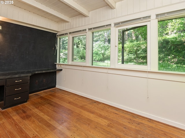 interior space featuring beamed ceiling, baseboards, plenty of natural light, and hardwood / wood-style flooring