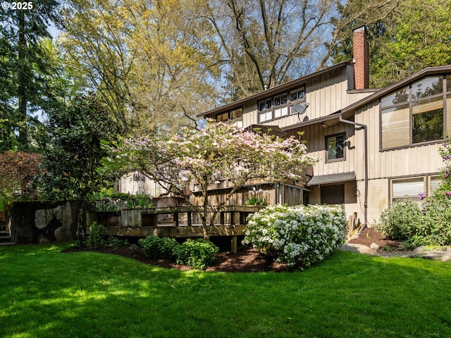 back of property featuring a lawn, a chimney, and a deck