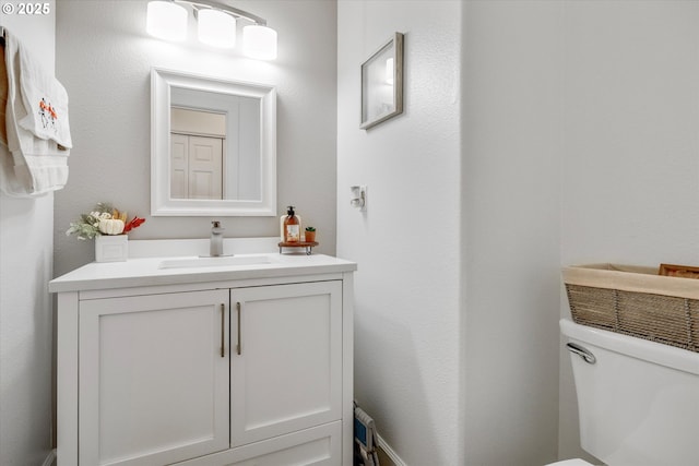 half bath featuring vanity and toilet