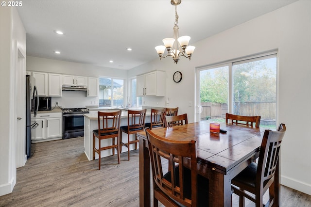dining space featuring light wood-style floors, an inviting chandelier, baseboards, and recessed lighting