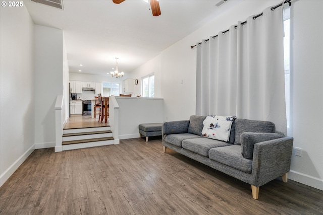 living room with ceiling fan with notable chandelier, visible vents, recessed lighting, wood finished floors, and baseboards