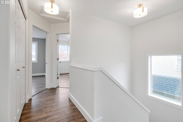 hallway with dark wood-type flooring, an upstairs landing, and baseboards
