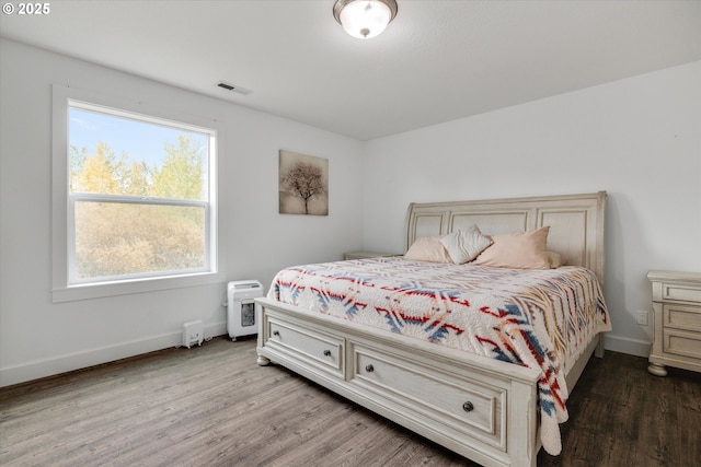bedroom with wood finished floors, baseboards, and visible vents