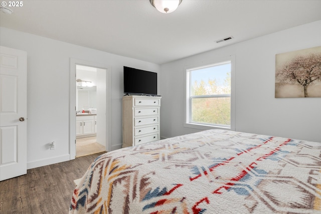 bedroom with visible vents, baseboards, ensuite bath, and wood finished floors