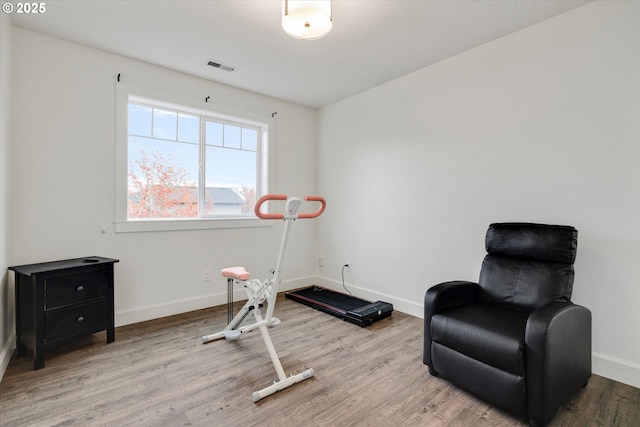 exercise area with visible vents, baseboards, and wood finished floors