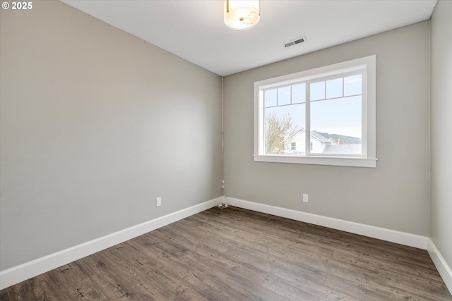 spare room with visible vents, baseboards, and wood finished floors