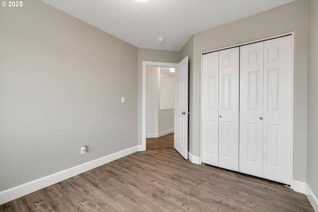 unfurnished bedroom with a closet, baseboards, and wood finished floors
