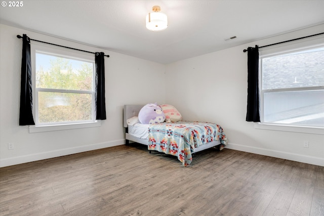 bedroom with visible vents, baseboards, and wood finished floors