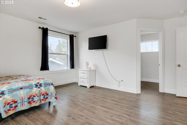 bedroom with visible vents, baseboards, and wood finished floors