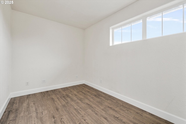 unfurnished room featuring dark wood-style flooring and baseboards