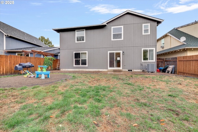 back of property featuring a yard, a fenced backyard, and central AC unit