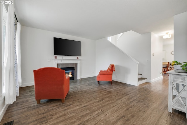 sitting room with a fireplace, visible vents, stairway, wood finished floors, and baseboards