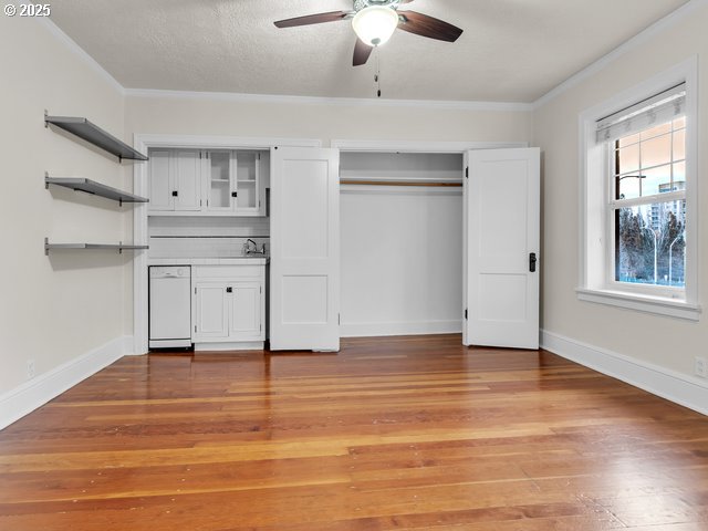 unfurnished bedroom with light wood-style floors, ornamental molding, a textured ceiling, and baseboards