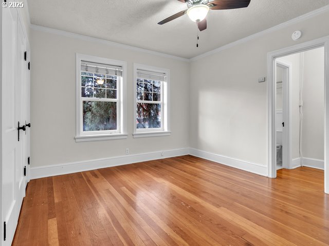 spare room featuring light wood finished floors, baseboards, ceiling fan, ornamental molding, and a textured ceiling