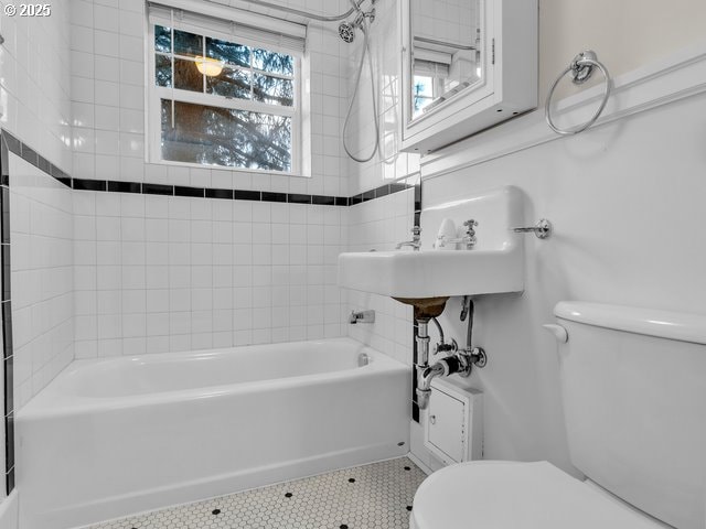 full bath featuring washtub / shower combination, tile patterned flooring, and toilet