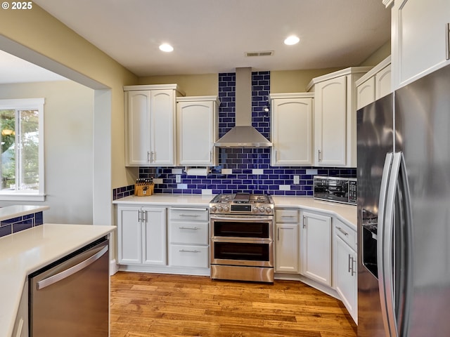 2231 SE Genesis Ct, Salem, OR 97306 - kitchen featuring appliances with stainless steel finishes, wall chimney range hood, white cabinetry, backsplash, and recessed lighting