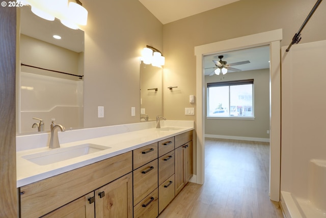 full bath featuring double vanity, baseboards, a sink, and wood finished floors