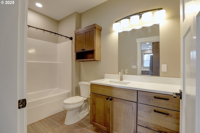 bathroom with toilet, washtub / shower combination, wood finished floors, and vanity