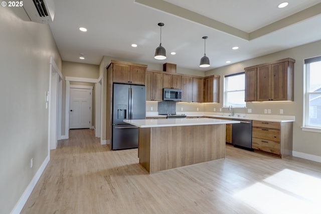 kitchen featuring a center island, pendant lighting, light countertops, appliances with stainless steel finishes, and a sink