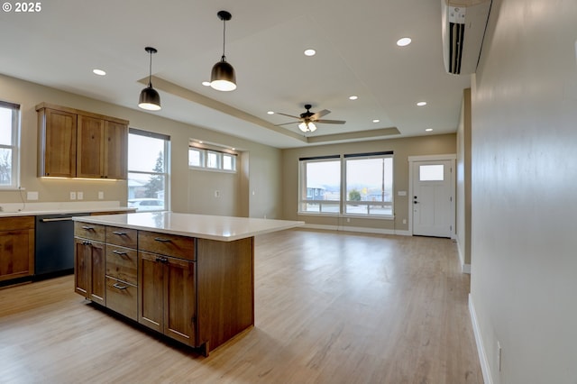 kitchen with black dishwasher, light countertops, a center island, a raised ceiling, and pendant lighting