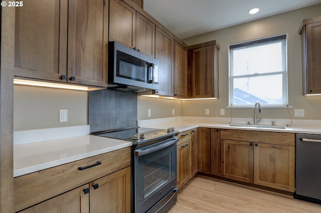 kitchen featuring brown cabinets, appliances with stainless steel finishes, light countertops, and a sink