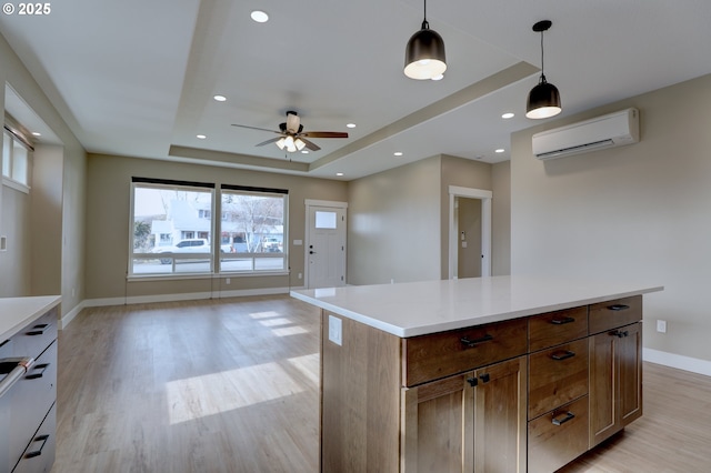 kitchen with a raised ceiling, a center island, hanging light fixtures, light countertops, and an AC wall unit