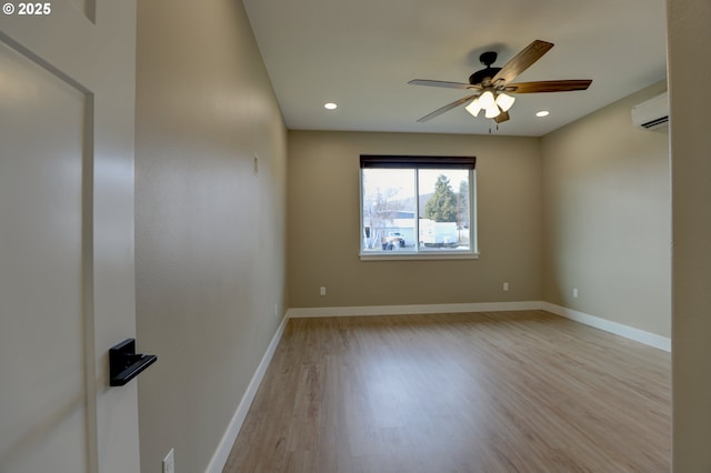 unfurnished room with recessed lighting, light wood-style flooring, baseboards, and a wall mounted air conditioner