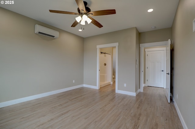 unfurnished bedroom with baseboards, ensuite bath, light wood-style flooring, a wall mounted air conditioner, and recessed lighting