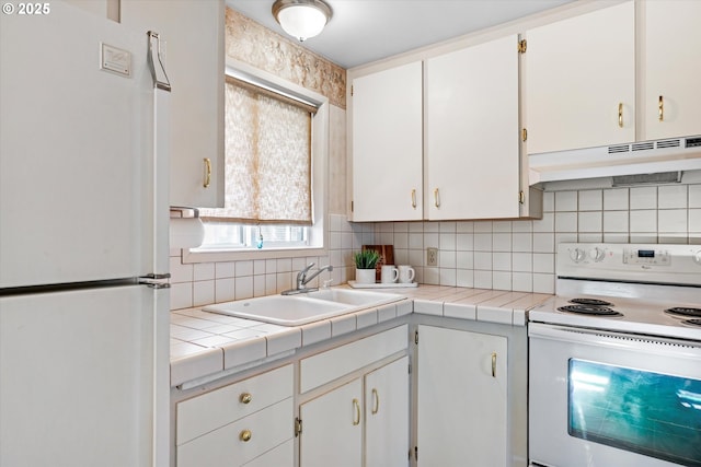 kitchen with white appliances, tile counters, sink, and white cabinets