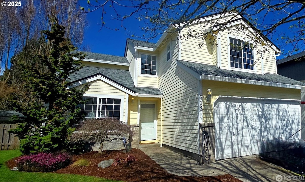 view of front of home with an attached garage, a shingled roof, and fence
