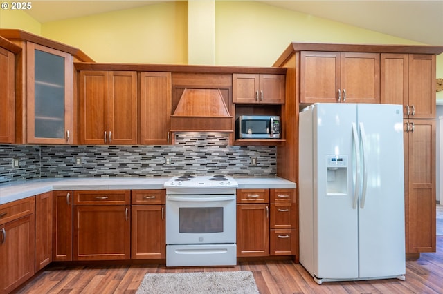 69143 Willow Rd, North Bend, OR 97459 - kitchen featuring white appliances, vaulted ceiling, premium range hood, light countertops, and tasteful backsplash