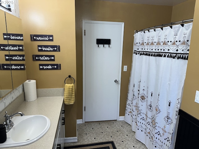 full bath with a shower with shower curtain, baseboards, and vanity