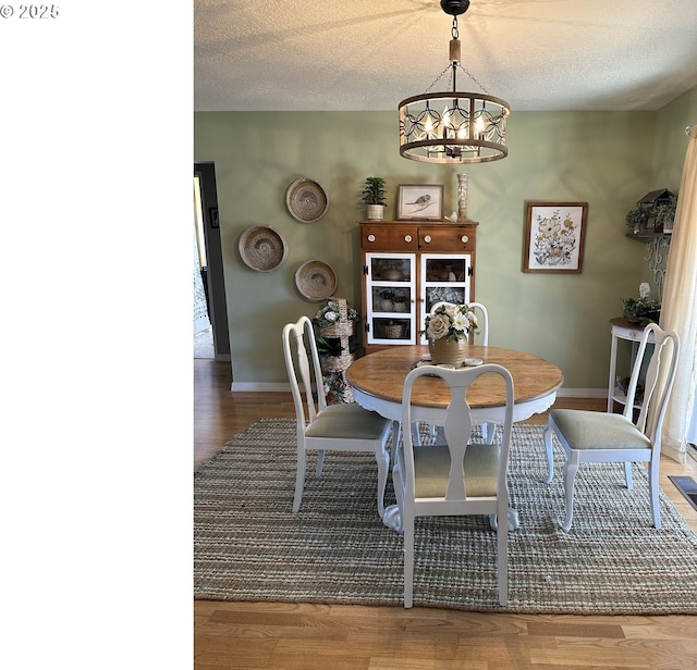 dining space with a notable chandelier, baseboards, and wood finished floors