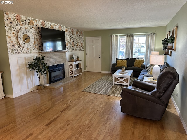 living area with a textured ceiling, wainscoting, a fireplace, and wood finished floors