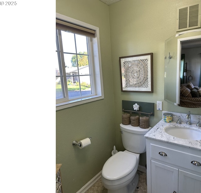 bathroom featuring toilet, vanity, visible vents, and baseboards