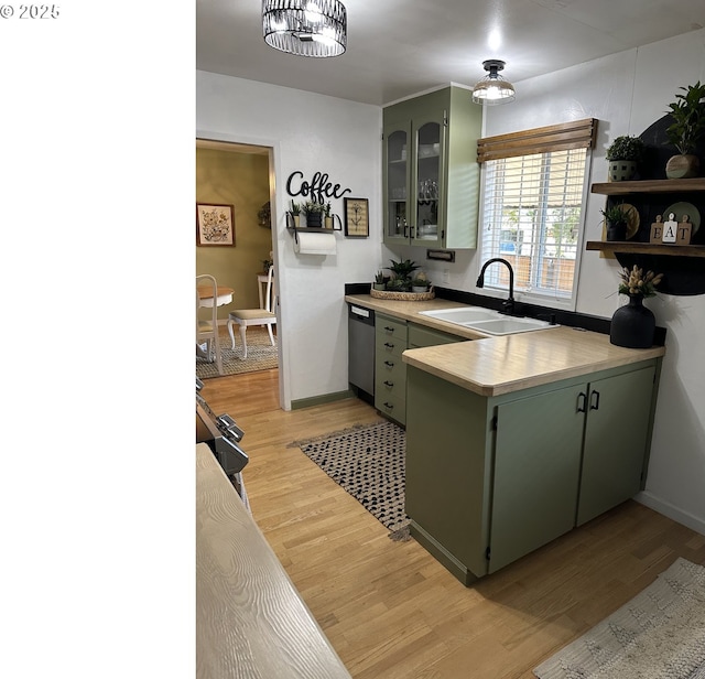 kitchen featuring light wood finished floors, dishwasher, a peninsula, a sink, and green cabinetry