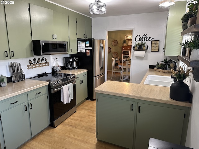 kitchen featuring a sink, light wood-style floors, light countertops, appliances with stainless steel finishes, and green cabinetry