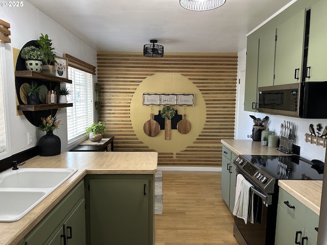 kitchen featuring a sink, green cabinets, light countertops, appliances with stainless steel finishes, and light wood-type flooring