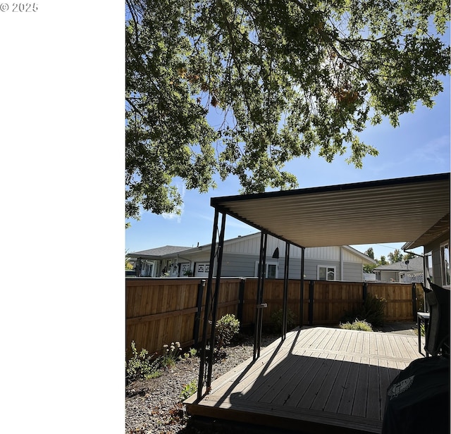 wooden deck featuring a carport and a fenced backyard