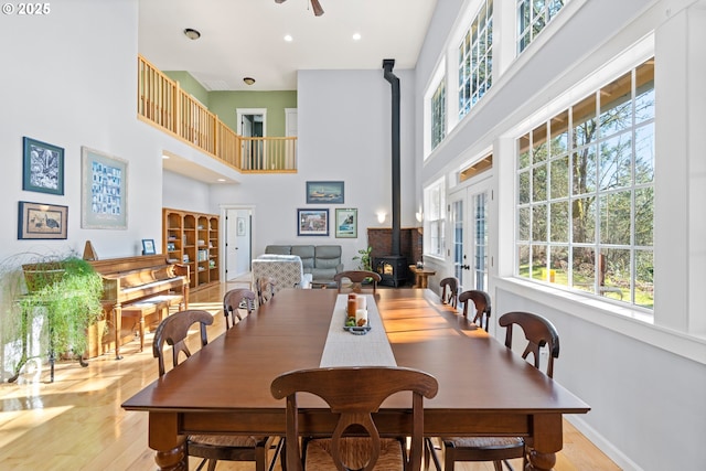 dining area with a wood stove, a healthy amount of sunlight, light wood-style flooring, and baseboards