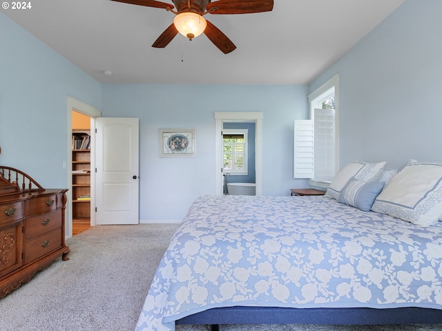 carpeted bedroom with ensuite bath and ceiling fan